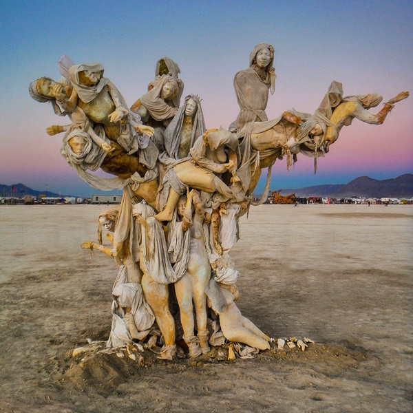 A tree-like cluster of shrouded figures rising from the desert floor at dusk
