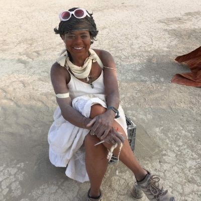 Portrait of artist Valerie Mallory smiling, seated on the playa